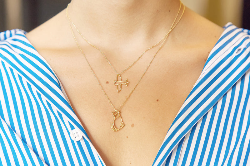 Gold chain necklaces with airplane and cat shaped pendants worn by model