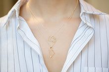 Load image into Gallery viewer, Gold chain necklace with dinosaur shaped pendant and small blue sapphire worn by model
