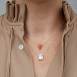 Model wearing gold chain necklaces with carrot shaped coral pendants and ghost shaped white coral pendant