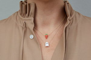 Model wearing gold chain necklaces with carrot shaped coral pendants and ghost shaped white coral pendant