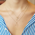 Gold chain necklace with chemistry baker shaped pendant worn by model