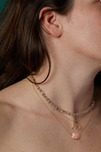 Model wearing gold necklace with topaz beads and crab shaped pink coral pendant