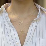 Gold chain necklace with dog shaped pendant and small diamond worn by model