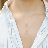 Gold chain necklaces with house and light bulb shaped pendants and small diamond worn by model