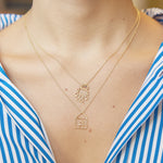 Gold chain necklace with robot shaped pendant and blue sapphires worn by model