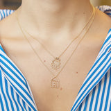 Gold chain necklace with robot shaped pendant and blue sapphires worn by model