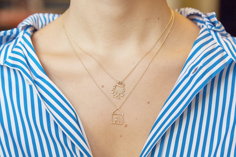 Gold chain necklace with robot shaped pendant and blue sapphires worn by model