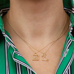 Gold necklaces with house and rabbit shaped pendants worn by model