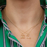 Gold necklaces with house and rabbit shaped pendants worn by model
