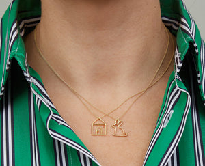 Gold necklaces with house and rabbit shaped pendants worn by model