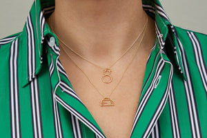 Gold chain necklaces with igloo and snowman shaped pendants worn by model