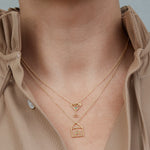 Gold necklaces with house and martini drick shaped pendants worn by model