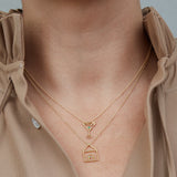 Gold necklaces with house and martini drick shaped pendants worn by model
