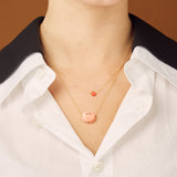 Gold chain necklace with sun shaped coral pendant worn by model