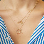 Woman wearing gold chain necklaces with small camera and rainbow shaped pendants with little stones