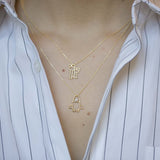 Gold chain necklace with space shuttle shaped pendant with pearl worn by model