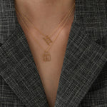 Gold chain necklace with stairs shaped pendant worn by woman