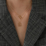 Gold chain necklace with stairs shaped pendant worn by woman