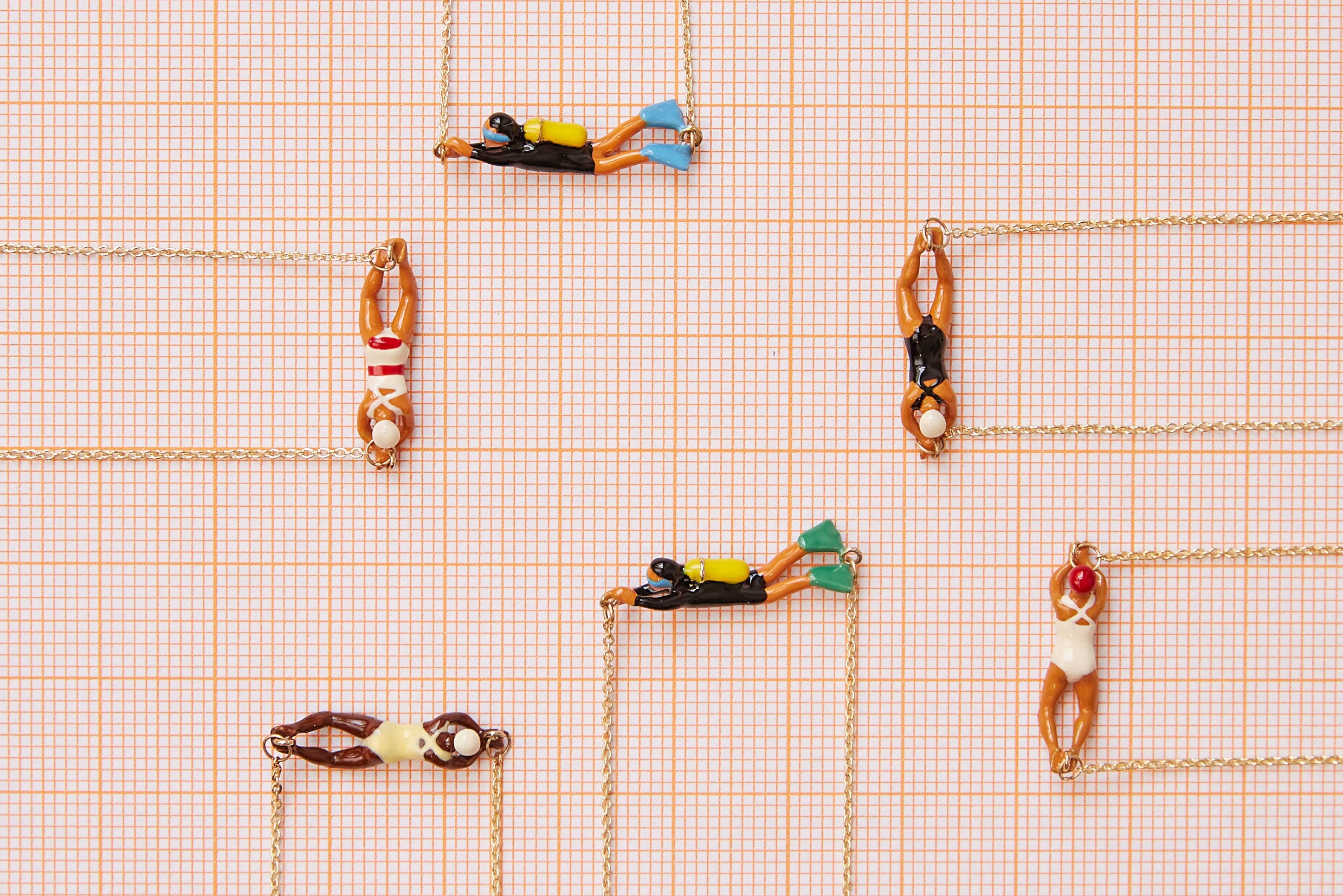 Jewelry composition with gold necklaces with swimmer and scuba divers shaped pendants