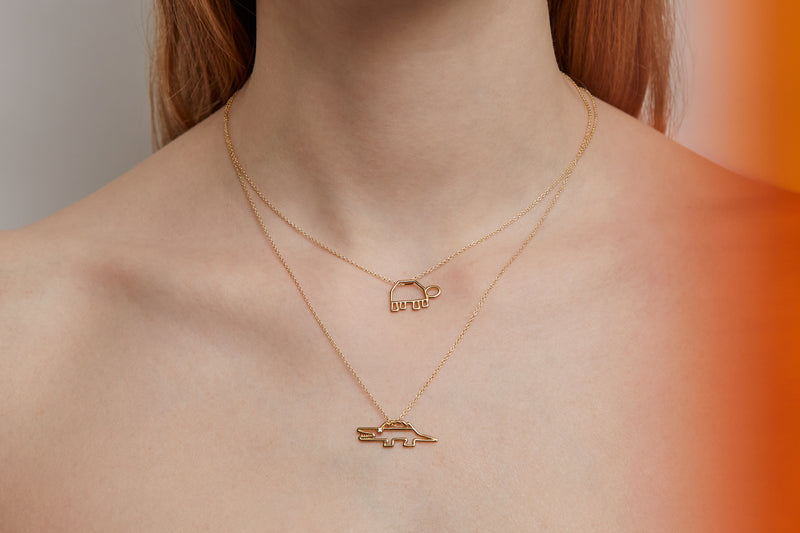 Woman wearing gold chain necklaces with turtle and crocodile shaped gold pendants