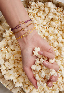 Hand holding pop corn with cord bracelets with light bulb and rabbit shaped gold  pendants