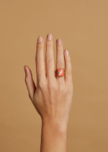 Gold ring with carrot shaped cameo in orange porcelain on model's hand