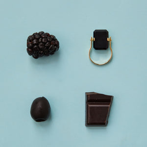 Composition with black food and gold ring with black agate