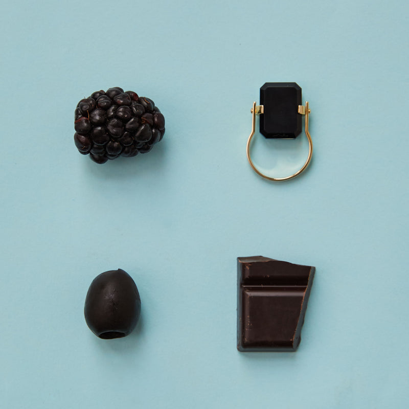 Composition with black food and gold ring with black agate
