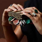 Hands holding paper sandwich wearing gold rings with hard stones
