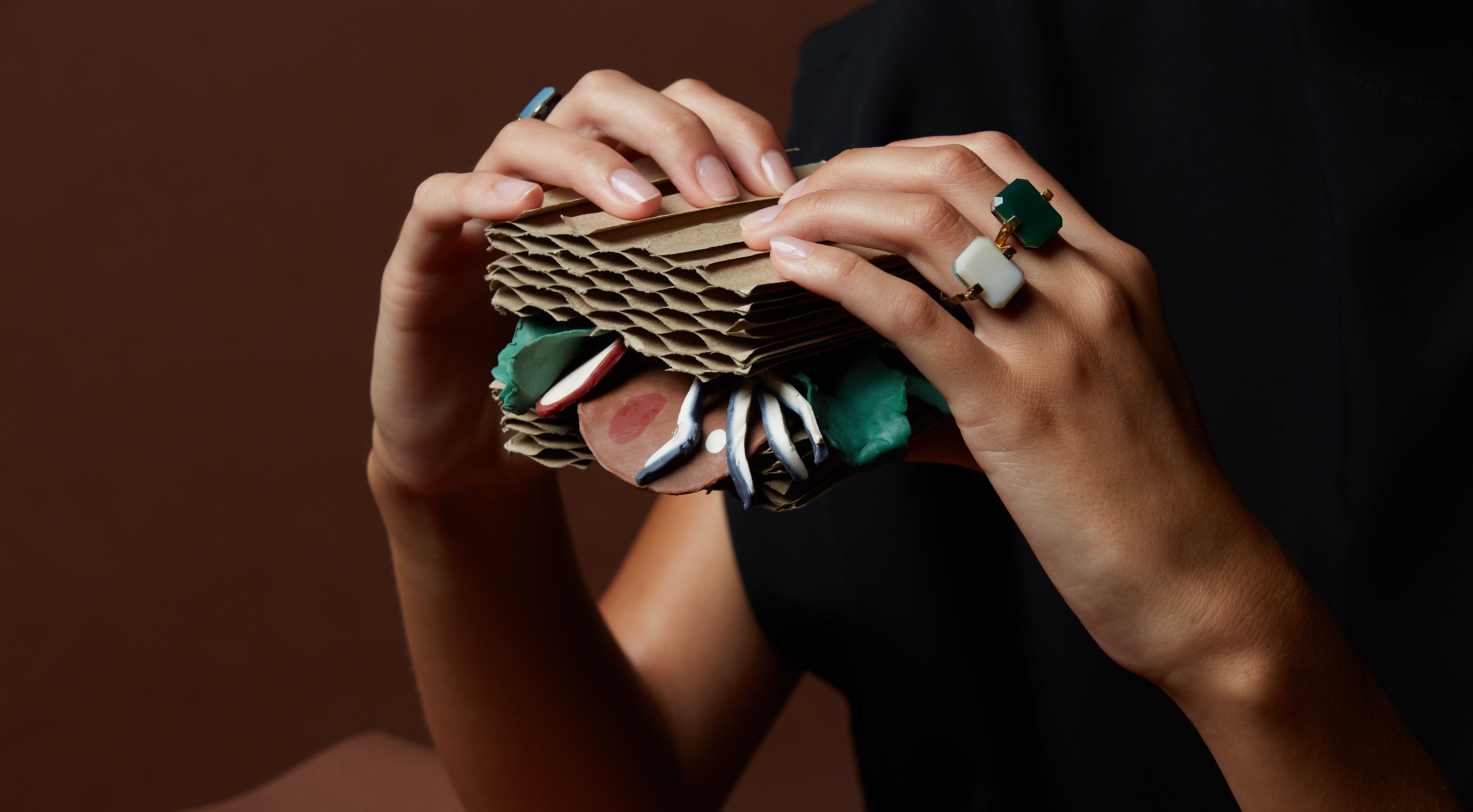 Hands holding paper sandwich wearing gold rings with hard stones