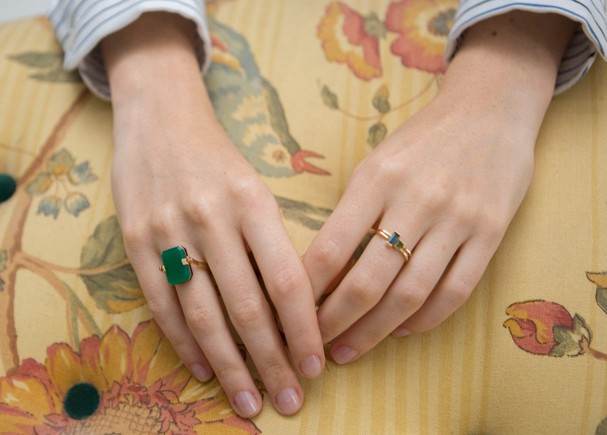 Hands wearing gold rings with precious stones