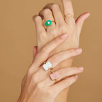 Hands wearing gold rings with turquoise and hard stones