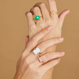 Hands wearing gold rings with turquoise and hard stones