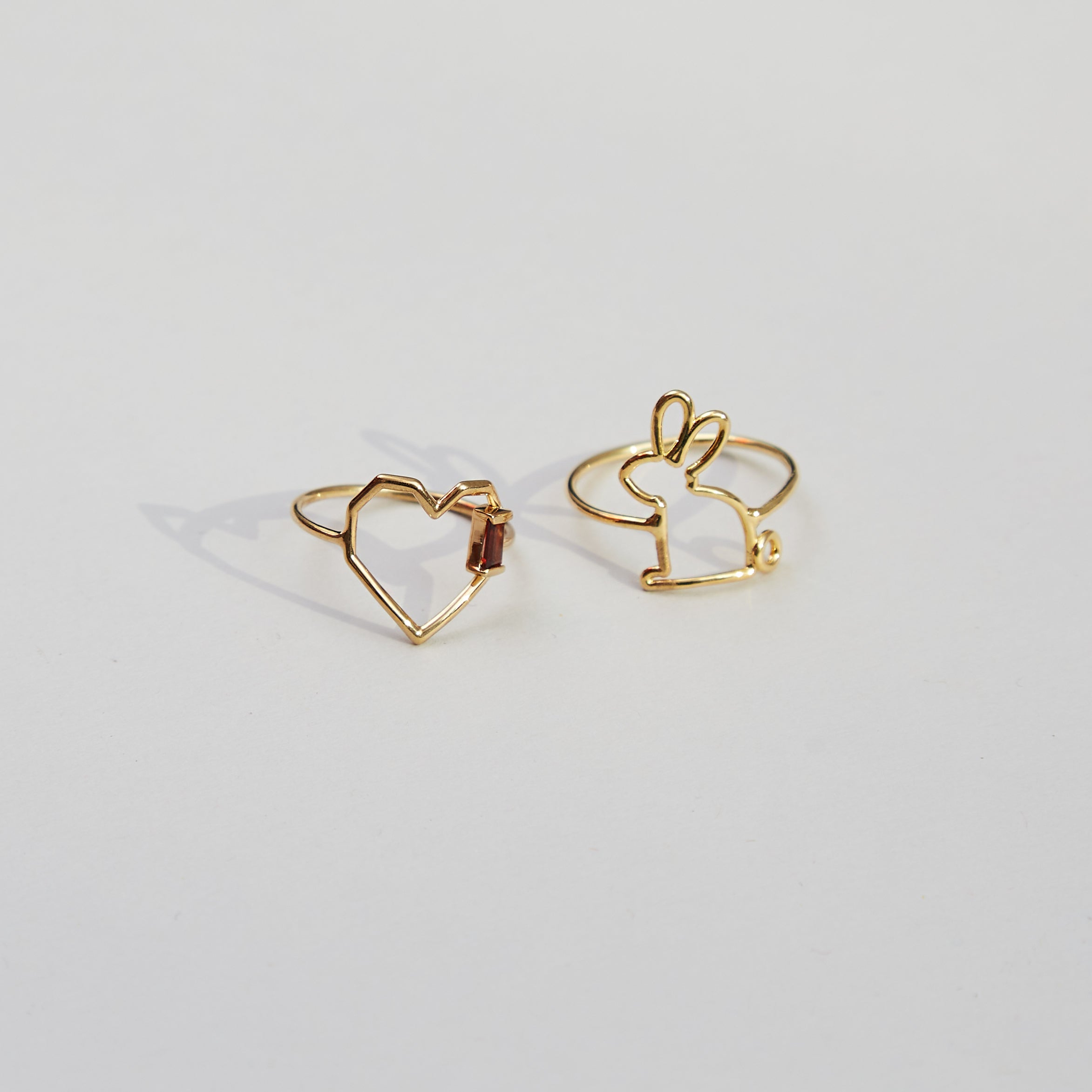 Gold rings shaped like a heart with a garnet baguette stone and a little rabbit
