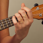 Gold seated cat shaped ring worn by model playing guitar