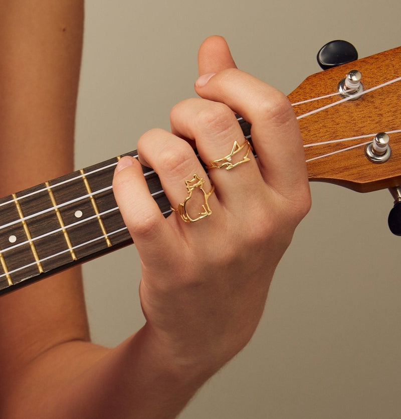 Gold seated cat shaped ring worn by model playing guitar