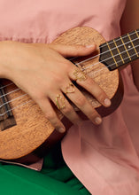 Load image into Gallery viewer, Hand playing guitar wearing gold rings with precious stones
