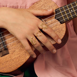 Gold robot shaped ring with blue sapphires as eyes worn by model playing ukulele