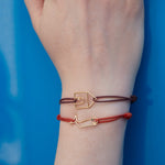 Cord bracelets with a house and whale shaped gold pendants with diamond and blue sapphire