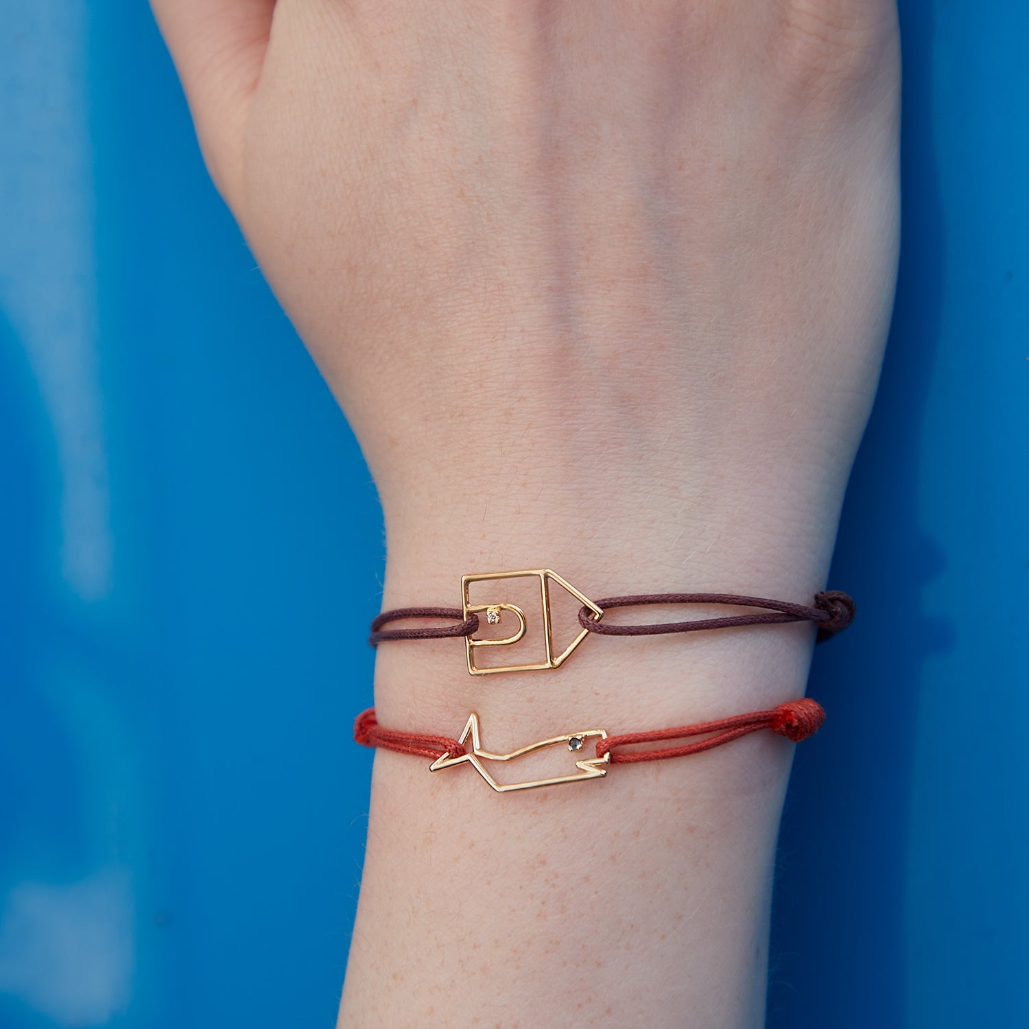 Cord bracelets with a house and whale shaped gold pendants with diamond and blue sapphire