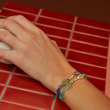 Woman weraing cord bracelets with tennis racquet shaped gold pendants