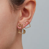 Seated cat shaped earring and heart shaped earring worn by woman