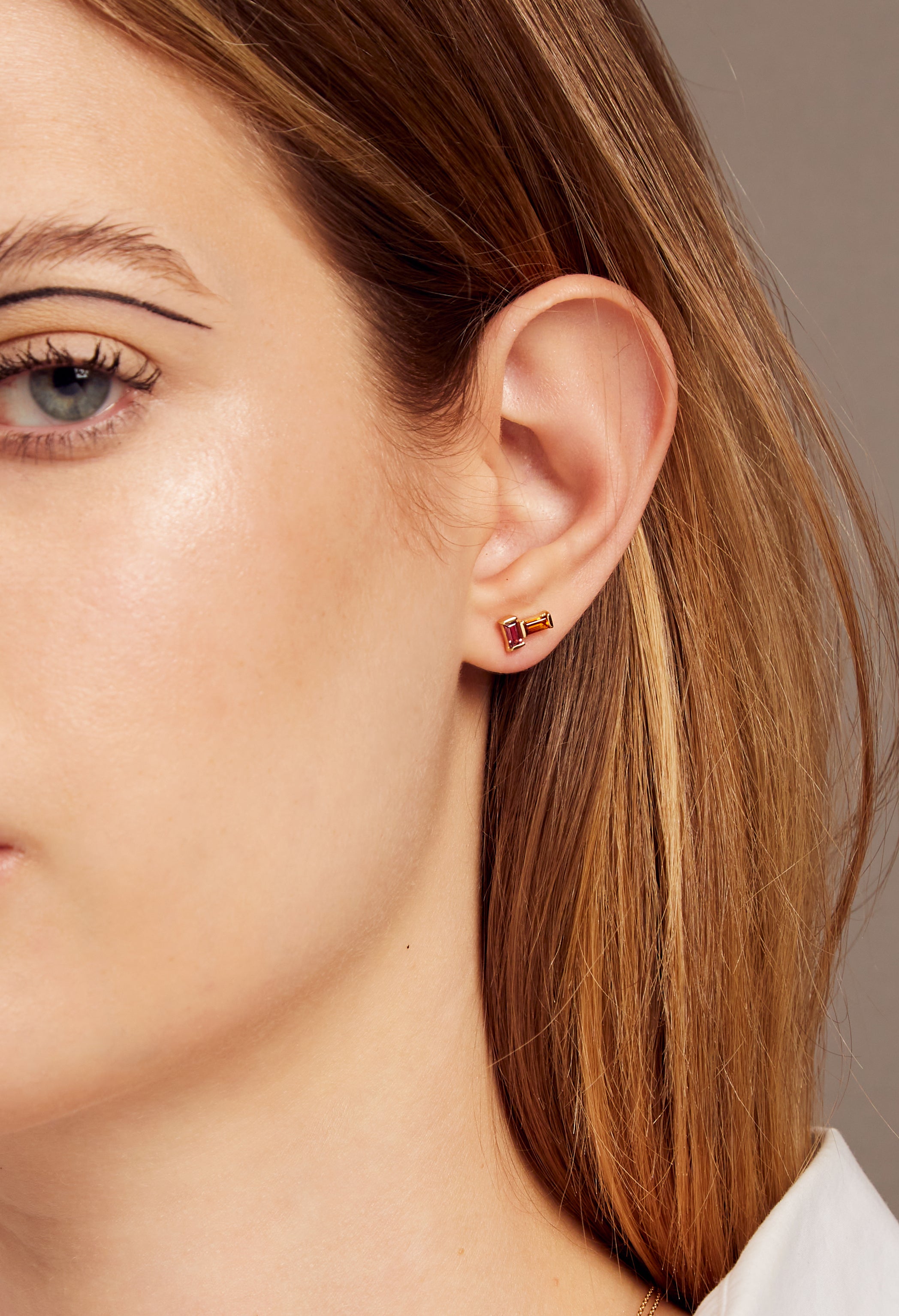 Gold earrings pair with baguette cut citrine and pink tourmaline worn by woman