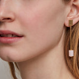 Woman wearing a gold long earring with cylinder cut pink opal
