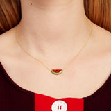 Woman wearing a gold chain necklace with a watermelon slice in red coral and oxidized turquoise