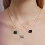Woman wearing gold chain necklaces with cylinder cut stones