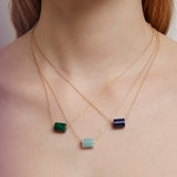 Woman wearing gold chain necklaces with cylinder cut stones