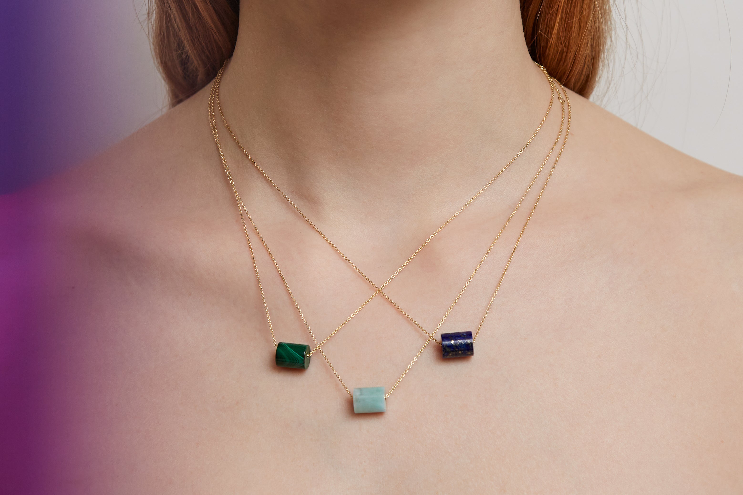 Woman wearing gold chain necklaces with cylinder cut stones