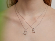 Load image into Gallery viewer, Woman wearing two white gold chain necklaces with a dog and rabbit shaped pendants

