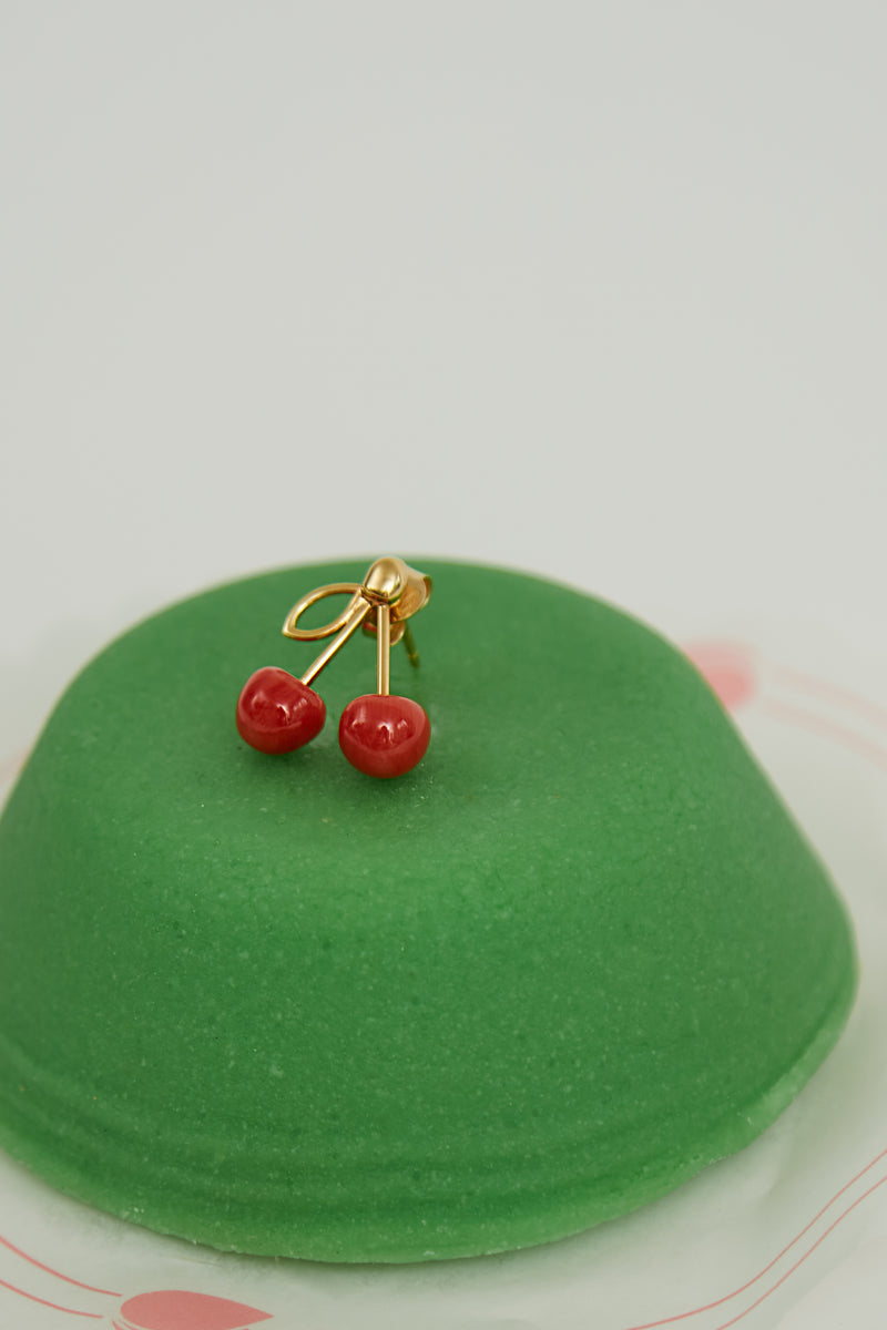 Green sweet pastry with coral cherries gold earring on top
